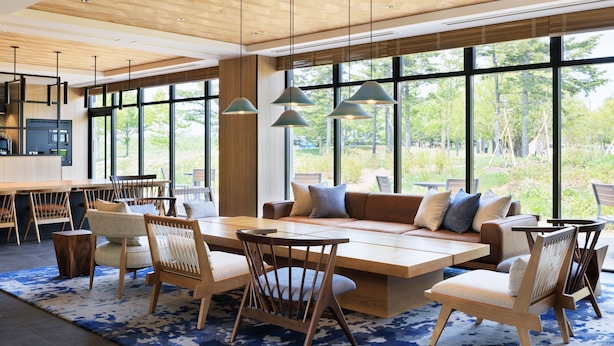 Een moderne woonkamer met een groot raam, houten meubels en hanglampen.