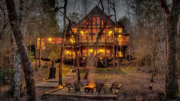 Une grande cabane en bois dotée de nombreux balcons et d’un espace aménagé avec un foyer, situé au premier plan.