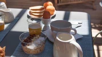 A breakfast setup with pancakes, eggs, and a coffee mug on a table.