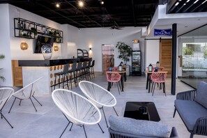 A modern bar area with white chairs, a counter, and a sign for 'Caffè Borbone'.