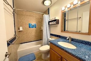 Een badkamer met een bad, toilet, wastafel en douchegordijn.