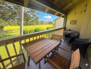 A wooden table and chairs on a porch with a view of a green landscape.