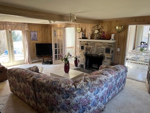 Relax in this inviting living room with a large sofa, stone fireplace, and large window.