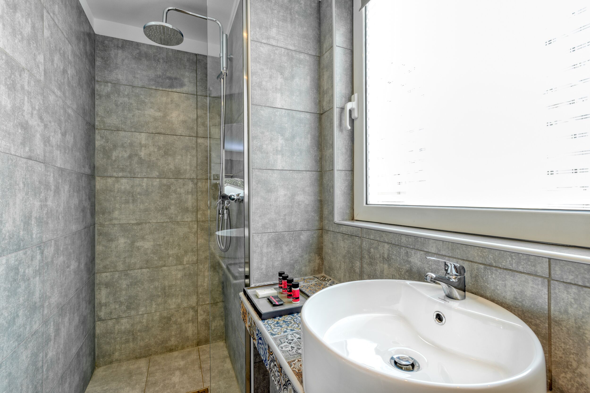 A modern bathroom with a shower, a sink, and a window.