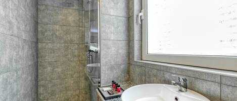 A modern bathroom with a shower, a sink, and a window.