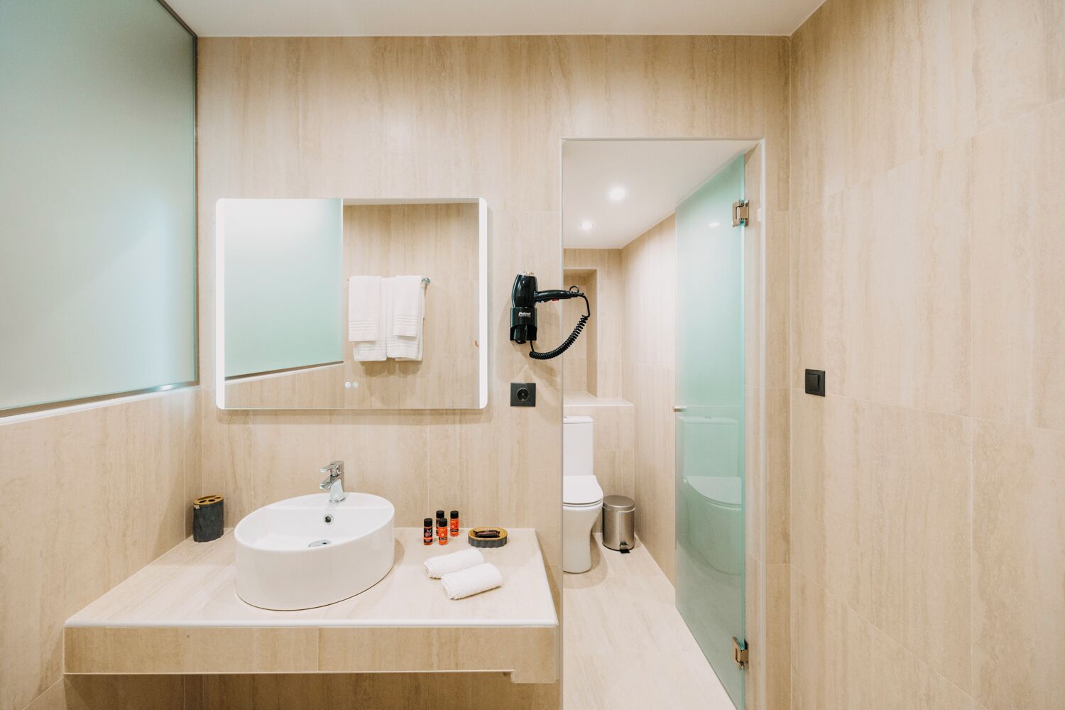Een moderne badkamer met een wastafel, spiegel en toilet.