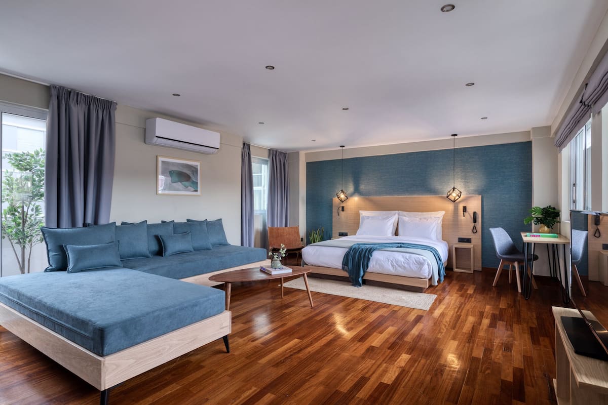 Una habitación de hotel moderna con una cama grande, un sofá, un escritorio y una mesa de comedor.