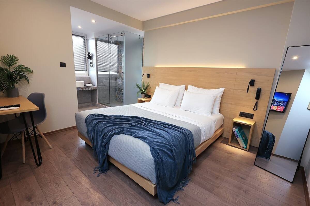 Una habitación de hotel moderna con una cama grande, un escritorio, una silla y una mesita.