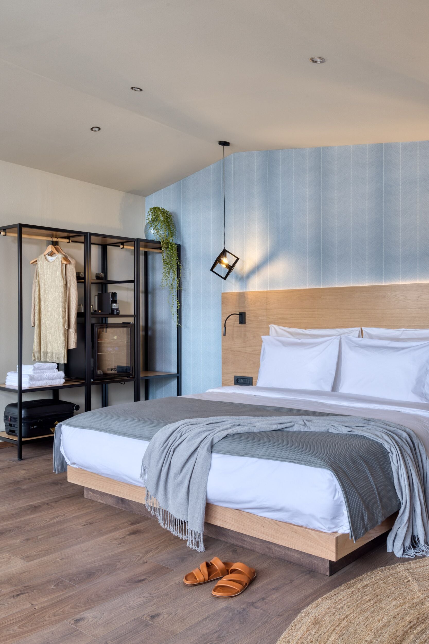 Ein modernes Schlafzimmer mit einem hölzernen Bett, einem Einbauschrank und einer hängenden Pflanze.