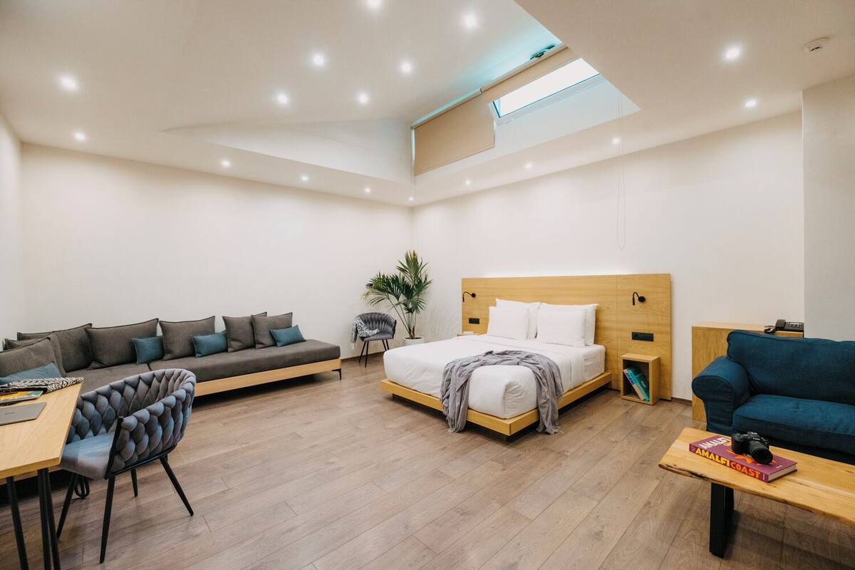 Una habitación de hotel moderna con sofá, cama, escritorio y silla.
