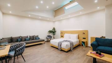 Quarto de hotel moderno com sofá, cama, escrivaninha e cadeira.