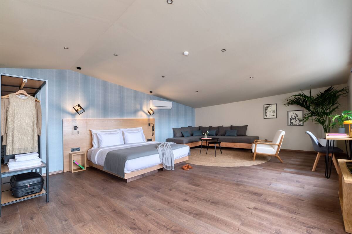 Una habitación de hotel moderna con una cama grande, un sofá, una zona de comedor y un armario.