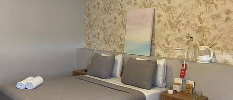 A bedroom with a bed, a bedside table, a wall-mounted air conditioner, and a painting.