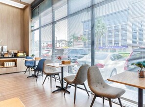 A modern interior with a dining area, large windows, and a view of the street.