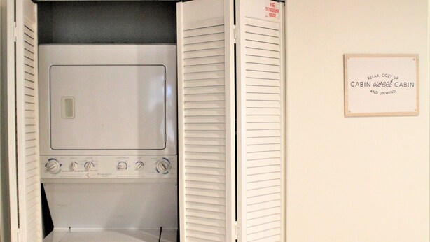 A laundry room with a washer and dryer, wooden flooring, and a sign on the wall. - HOT TUB•MOVIE ROOM•GAME ROOM•DOGS ALLOWED•CENTRALLY LOCATED•FENCED IN PROPERTY (Big Bear Lake)