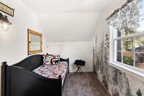 Une chambre à coucher avec un lit, un miroir, une fenêtre et une lampe.