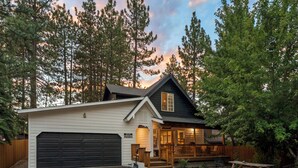 A two-story house with a garage, a covered porch, and a stone patio. - HOT TUB•MOVIE ROOM•GAME ROOM•DOGS ALLOWED•CENTRALLY LOCATED•FENCED IN PROPERTY (Big Bear Lake)