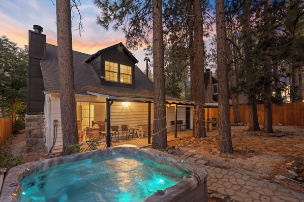 A house with a hot tub, outdoor seating, and a covered patio area.
