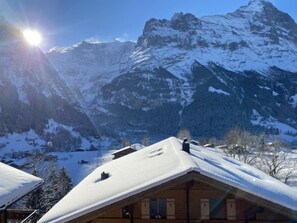 A mountain cabin with a snow-covered roof, surrounded by snow-covered trees and mountains. - Chalet Snowflake by Interhome (Grindelwald)