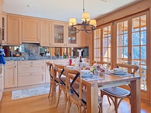 A spacious kitchen with wooden cabinets, a marble countertop, and a dining area with a table set for six.