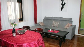 A living room with a grey sofa, a red table with a bottle and glasses, and a painting on the wall. - Apartment for 3- 4 people in the center of Pula (Pula)