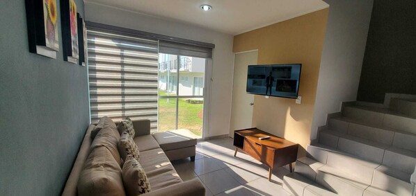 A modern living room with a sofa, a coffee table, and a TV mounted on the wall.