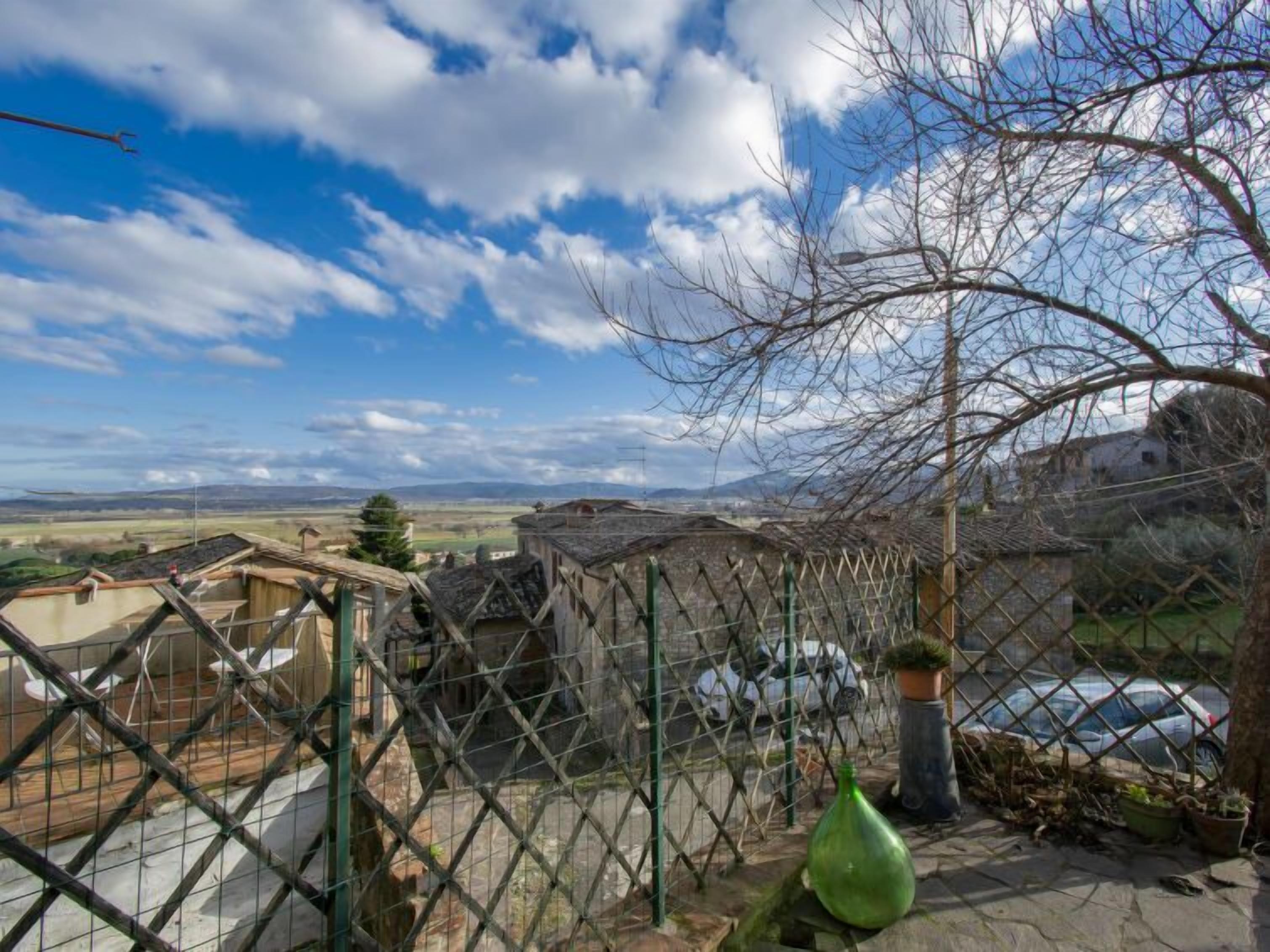 A fenced outdoor area with a view of a rural landscape, including houses and a car.