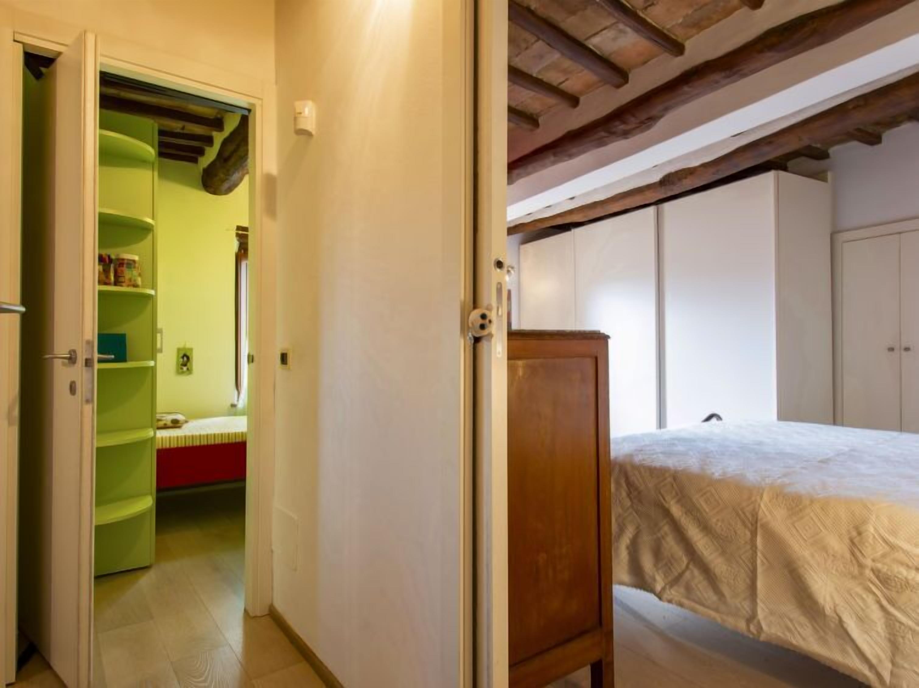 A bedroom with a bed, a wardrobe, and a green shelf unit.