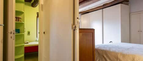 A bedroom with a bed, a wardrobe, and a green shelf unit.