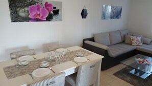 Uma sala de jantar com uma mesa posta para quatro pessoas, um sofá e uma mesa de centro.