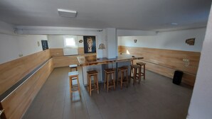 Uma cozinha com balcão e banquetas de madeira, um quadro de leão e um radiador.