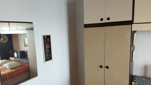 Een slaapkamer met een bed, een kast en een spiegel die een deel van de kamer weerkaatst.