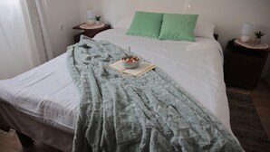 A neatly made bed with a green polka dot pillow, a bowl of fruit, and a book on the bed. - Apartment Amigo - Two Bedroom Apartment with Terrace (Đurđevac)