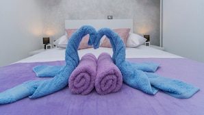 Ein modernes Hotelzimmer mit einem Bett, zwei Nachttischen und einer Wandablage mit Dekoration.
