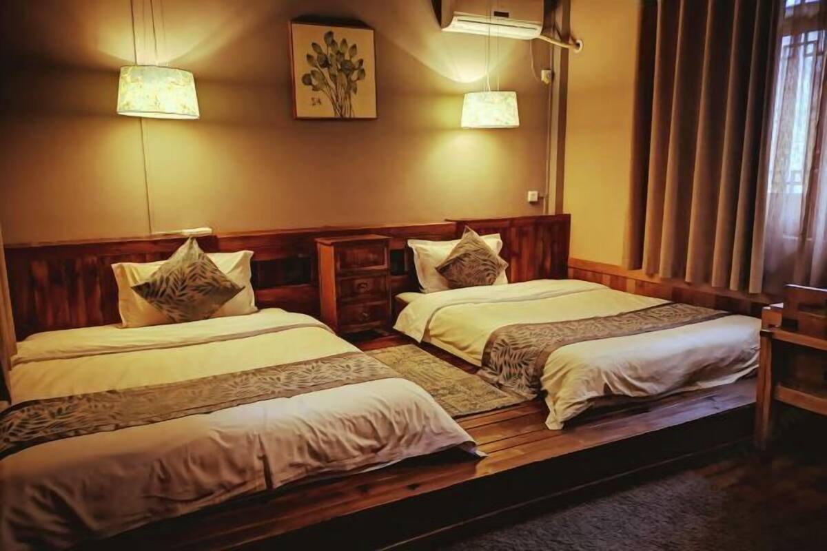 A double room with two beds, wooden headboards, and a large window with curtains.