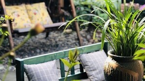 A green bench with plaid cushions, a potted plant, and a yellow patterned cushion in the background. - Fanhua Courtyard (Chongqing)
