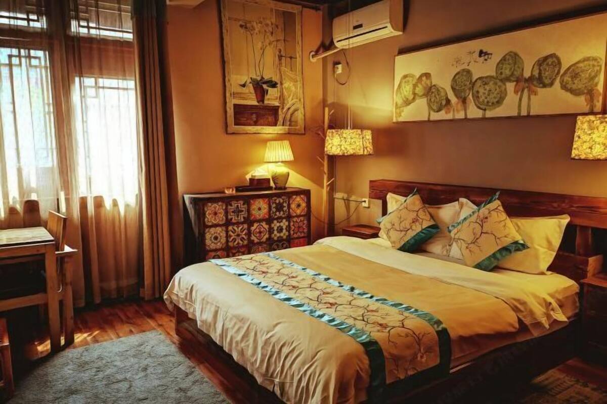 A neatly arranged bedroom with a large bed, bedside lamps, a wooden nightstand, and a chair.