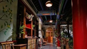 A narrow hallway with wooden furniture, a tiled floor, and a red pillar. - Fanhua Courtyard (Chongqing)