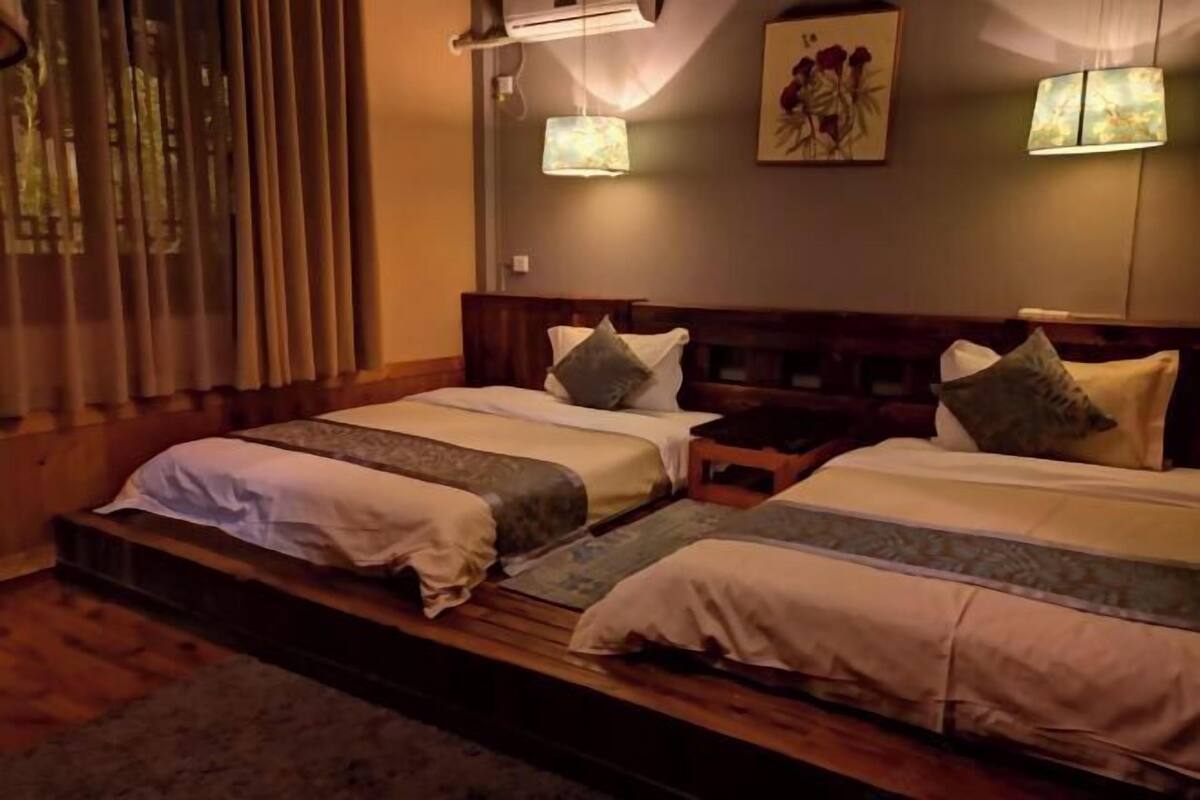 A double bed with a wooden headboard, two bedside tables, a nightstand, and a wall-mounted lamp.