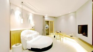 A modern hotel room with a large bed, a TV, a small table, and a chair. - Haolilai Garden Hotel (Sanming)