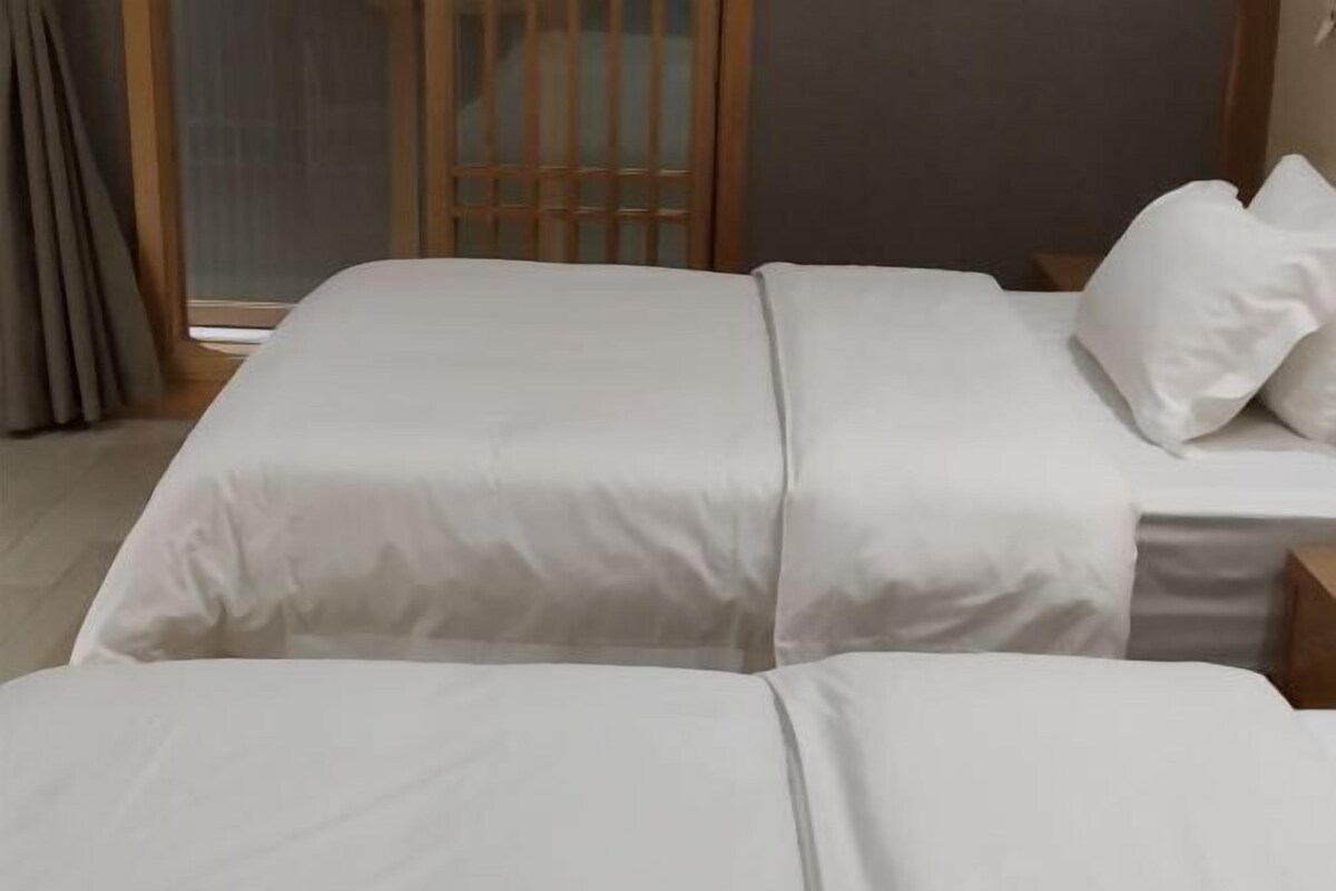 A hotel room with a bed, a nightstand, and a window with curtains.