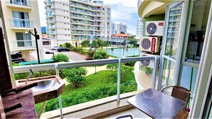 Een balkon met uitzicht op een zwembad, een tuin en aangrenzende gebouwen.