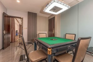 Une table de billard avec quatre chaises, un luminaire au plafond et une porte à l  ’arrière-plan.