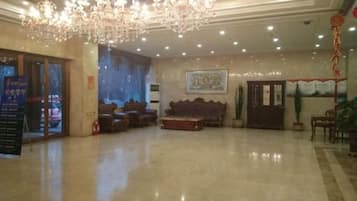 A spacious lobby with a chandelier, seating area, and a reception desk.