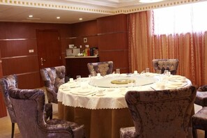 Une table de salle à manger ronde, recouverte d’une nappe blanche, entourée de chaises rembourrées.