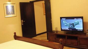 Habitación de hotel con cama, televisor, armario y un cuadro en la pared.