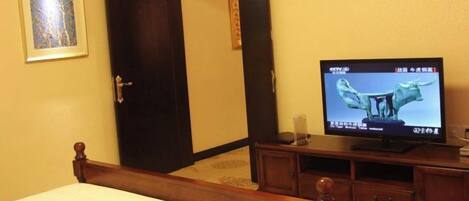 Habitación de hotel con cama, televisor, armario y un cuadro en la pared.