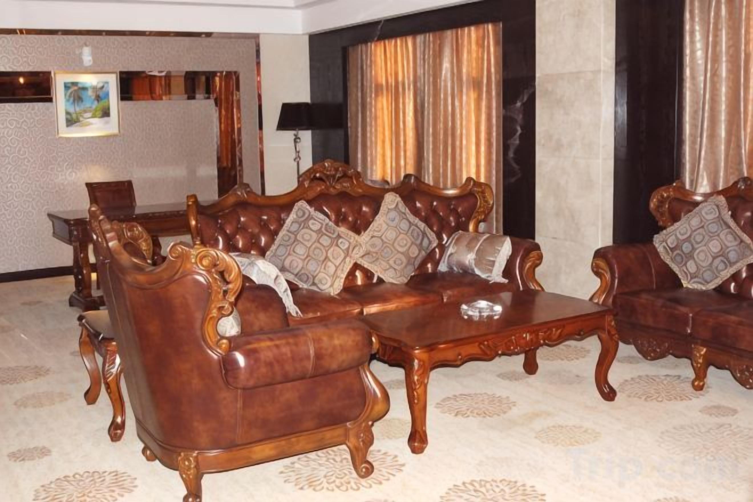 A room with a large, ornate sofa set, a coffee table, and a patterned carpet.