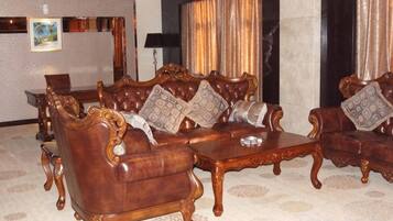 A room with a large, ornate sofa set, a coffee table, and a patterned carpet.
