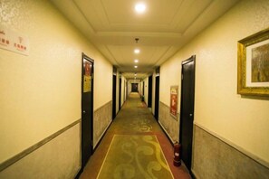 A hotel corridor with doors on both sides, a patterned carpet, and a fire extinguisher on the right. - Lanyi Holiday Hotel (Kelan)